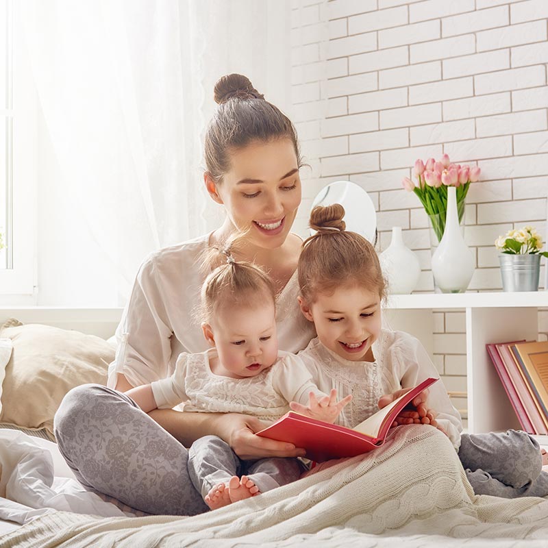 Mother reading with baby and toddler